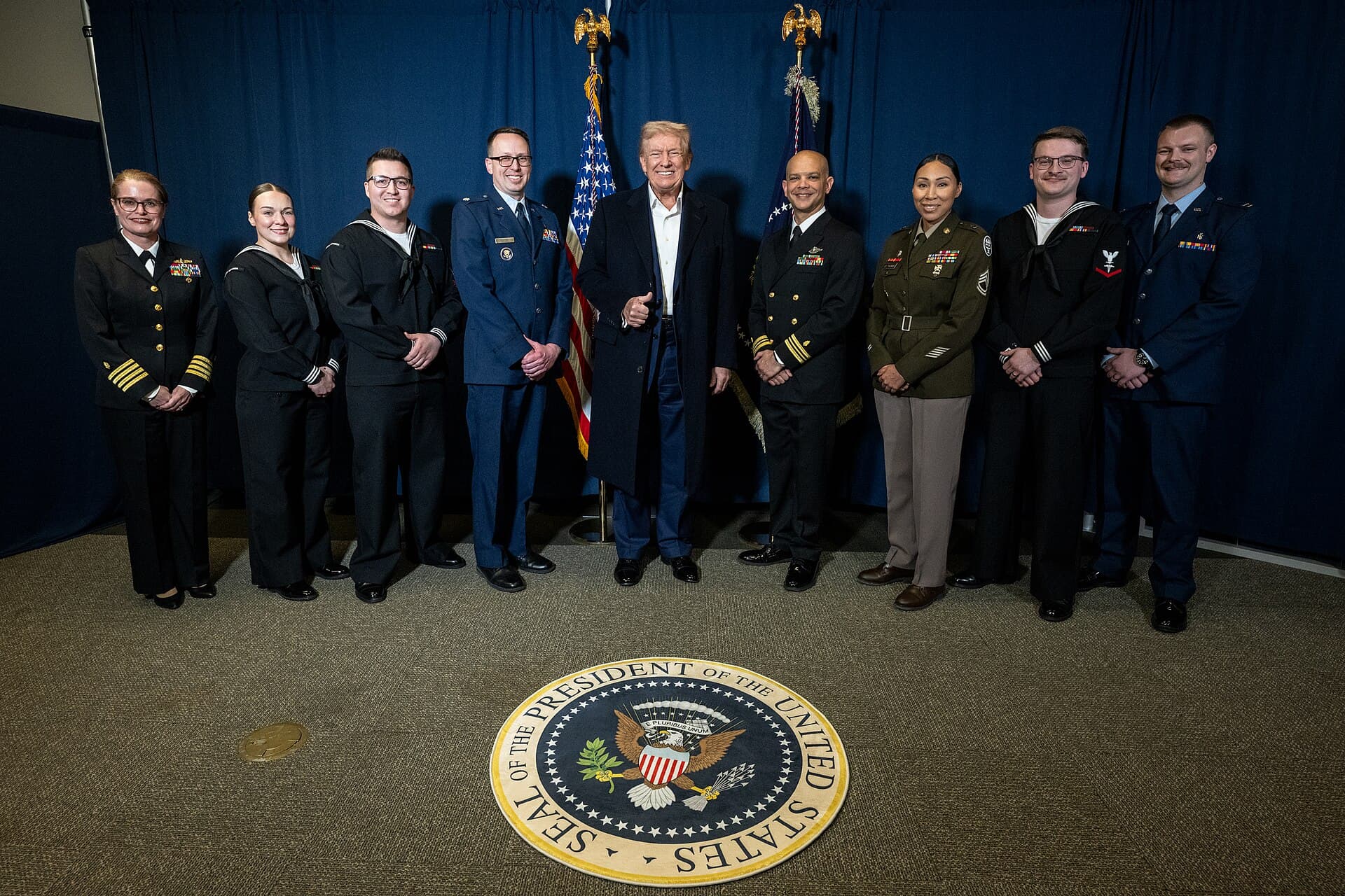 President Donald Trump gives a thumbs-up while posing with military medical staff at Walter Reed in April 2025